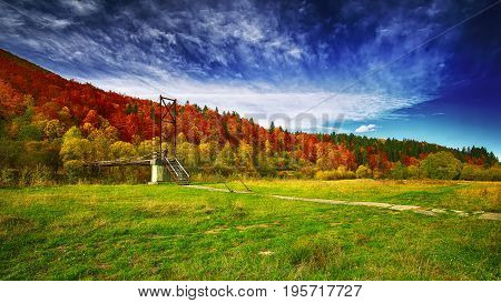 Wooden bridge over mountain river. Dramatic dark sky. Autumn time