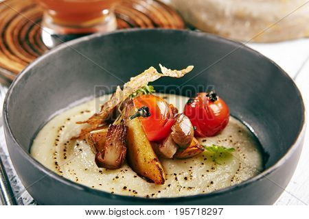 Restaurant Soup Food - Delicious Mushroom Soup with Garlic and Cherry Tomato. Gourmet Restaurant Soup Menu. Mushrooms Soup Garnished with Tea Broth and Garlic Mousse