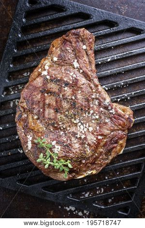 Barbecue dry aged Rib of Beef with salt and pepper as top view on a grillage 