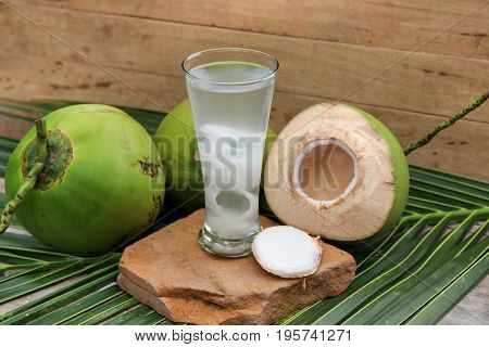 Fresh Coconut Water Drink in glass with coconut leaf on wooden  background