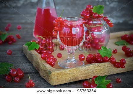 liqueur of red currant in the glass and fresh berries on the old background