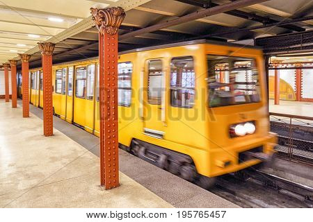 Fast yellow train coming on empty subway Opera station in Budapest Hungary