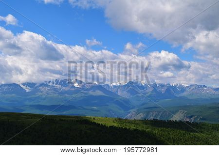 White peaks of North-Chuysky ridge and green fields of Kurai steppe in Altai mountains. Altay Republic Siberia Russia.