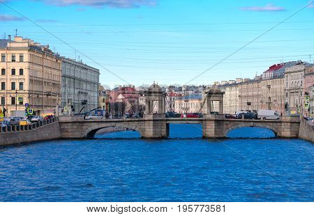 SAINT PETERSBURG RUSSIA - MAY 3 2017: Evening view of Lomonosov Bridge across Fontanka River St. Petersburg Russia. Unknown people walking down street