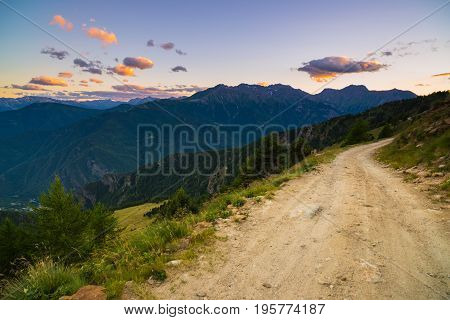 Dirt Mountain Road Leading To High Mountain Pass In Italy. Expasive View At Sunset, Colorful Dramati