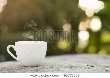 White cup morning coffee in garden and sunrise.