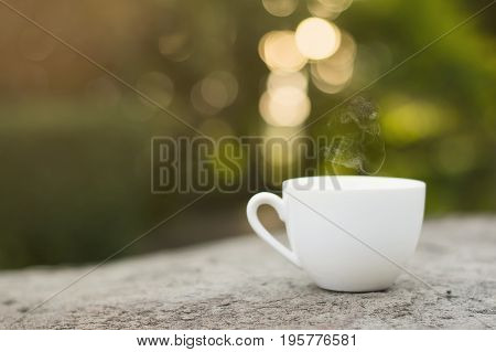 White cup morning coffee in garden and sunrise.