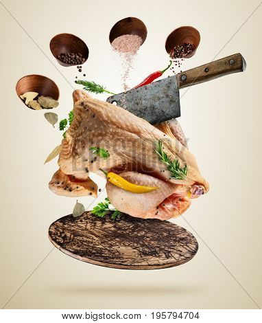 Whole raw chicken with ingredients for cooking, served on woodenboard. Concept of food preparation in low gravity mode. Separated on smooth background. High resolution image