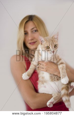 Beautiful young blonde woman holging her ginger cat.