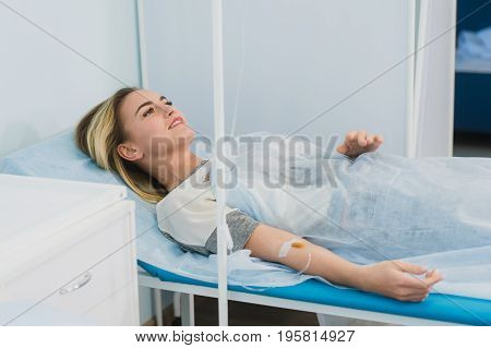 Pensive woman transfused lying in hospital ward.