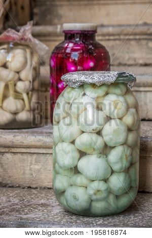 Seasoning pickled white and pink marinated garlic in glass jar at wine region of Kaheti, Georgia.
