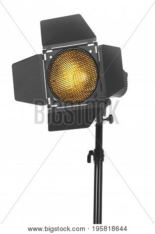 Close-up of black studio lighting on a tripod stand, isolated on the white background. Photo-studio with lighting equipment. The photo of the honeycomb is glowing.