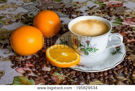 Cup of fresh Coffee with orange on a table with grains in the morning