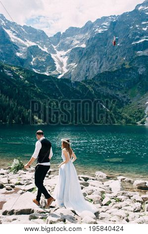bride with the beautiful blue dress and groom with views of the beautiful green mountains and lake with blue water