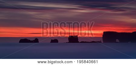 Rocks of Dyrholaey peninsula in colorful sunset Iceland