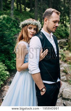 beautiful bride in a blue dress and a wreath of white flowers with the bride are in the wood.
