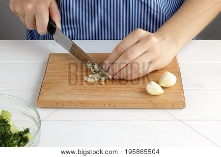 Step By Step Recipe For Tarator. Hands Cut A Garlic On Board In The Kitchen.