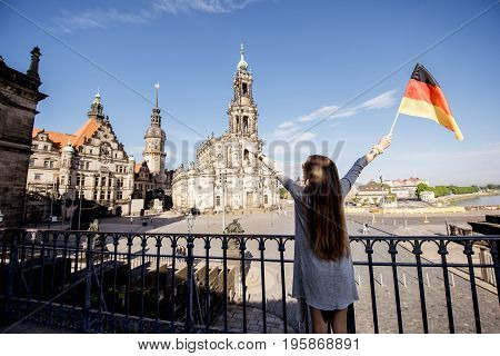 Young woman tourist with german flag enjoying great view on the Schlossplatz in Dresden city during the morning light