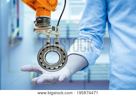 Industry robotic picked a spherical roller bearings on the right hand of engineers in blue tones color background, industry 4.0. concept
