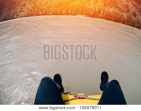 man in the wetsuit sits on the edge of the boat, rafting