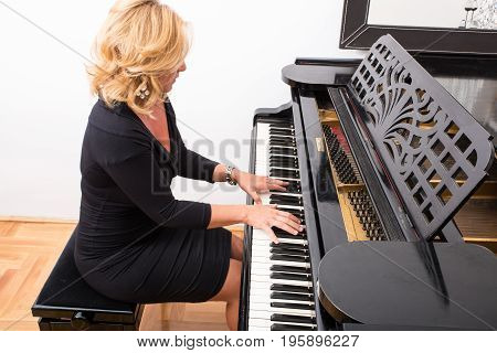 Hands of an elegant classical musician woman playing on piano.
