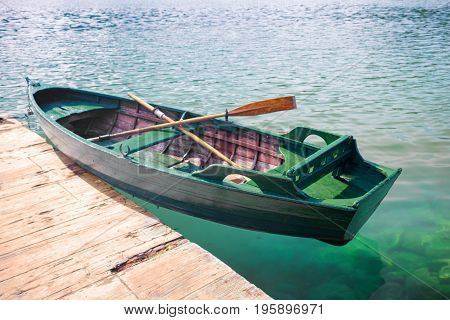 green wooden fishing boat on clear water near the pier