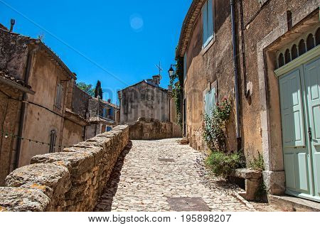 View of typical stone houses with sunny blue sky, in an alley of the historical village of Ménerbes. Located in the Vaucluse department, Provence-Alpes-Côte d'Azur region, southeastern France