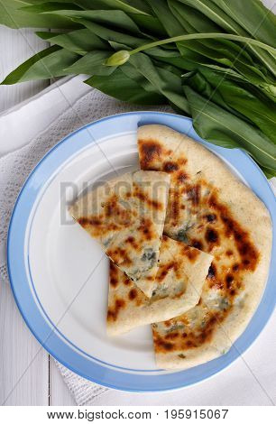 Khychiny - traditional caucasian flatbread filled with сheese and herbs. Flat bread stuffed with feta and wild garlic. Top view.