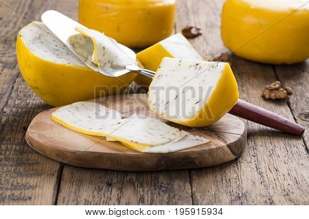 Goat herbs cheese and cheese slicer on wooden table