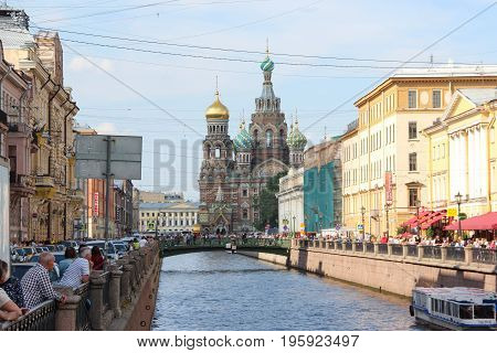 St. Petersburg, Russia - July 13 2017: Historic, picturesque griboyedov canal and street to Church on spilled blood full of pedestrians. Summer day, crowd of tourists. Water with the excursion boat