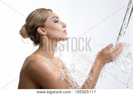 Young happy girl catching water stream and splashes falling in her hands studio shot