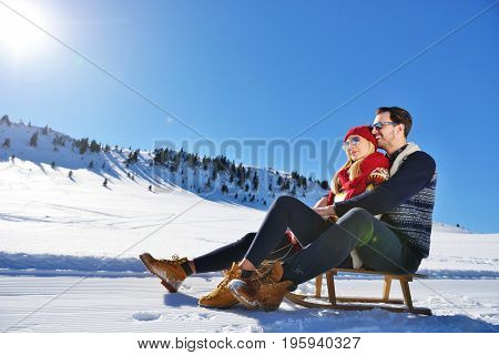Young Couple Sledding And Enjoying On Sunny Winter Day.