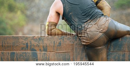 Mud race runners running over obstacles extreme sport
