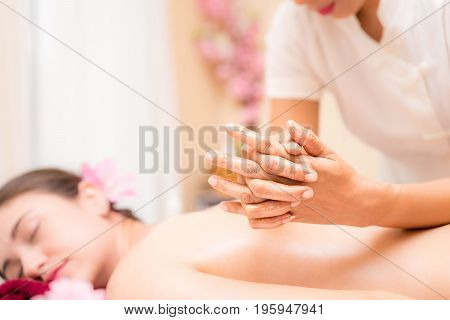 Spa Therapist is massaging women back with her elbow.