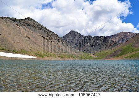Lake with waves and snow in Altai mountains. Altay Republic Siberia Russia.