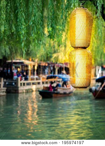 Suzhou, China - Nov 5, 2016: Brightly lit Chinese lanterns in front of waterway, boats and willows at the historic Zhouzhuang Water Town.