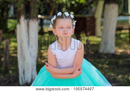 cute girl dressed in blue and white dress with a wreath of artificial flowers on her head embracing herself child in a festive dress on a nature background