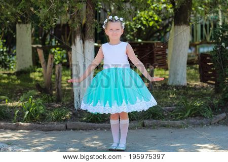 Beautiful Little Girl In Dress Standing And Posing Over Nature Background, Child With A Wreath Of Ar