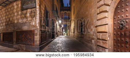 cobbled medieval Carrer del Bisbe street with Bridge of Sighs in Barri Gothic Quarter at night, Barcelona, Catalonia, Spain