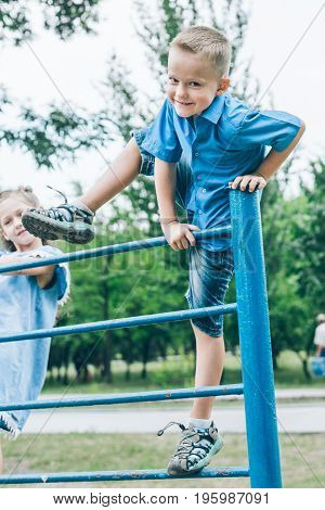kid playing on horizontal bar in summer park