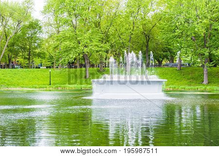 Montreal Canada - May 26 2017: Green fountain and lake in La Fontaine Park in Quebec region city during summer