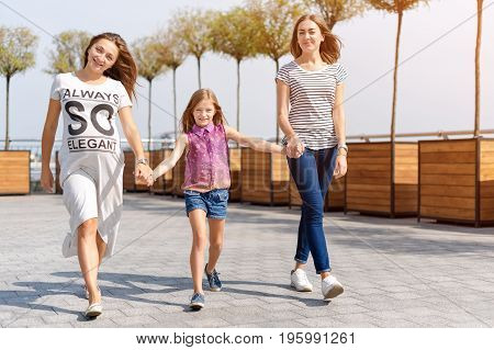 Samesex lesbian family with child on a walk in the park near the river. Lesbians mothers with adopted child, happy family, pregnant couple with kid