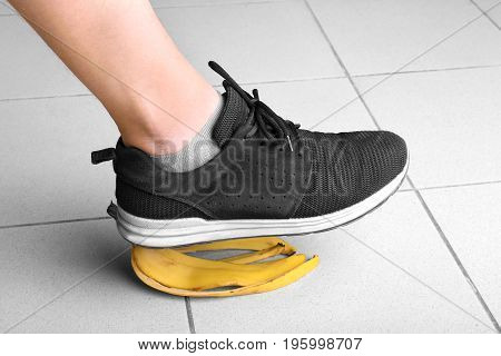 The guy stumbles on the peel of a natural, ripe, organic bright yellow banana on a gray background. Risk and danger concept. Incidence.