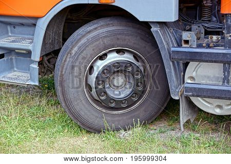 Front wheel of truck and part of car in green grass