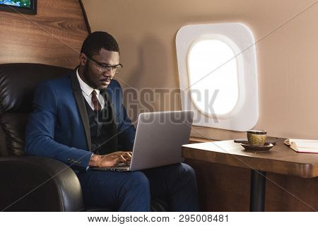 Attractive And Successful African American Businessman With Glasses Working On A Laptop While Sittin