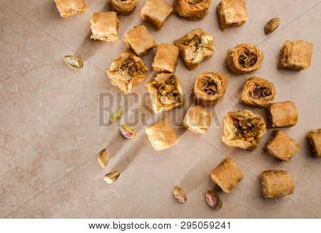 Assorted turkish Baklava with whole pistachio nuts scattered around.