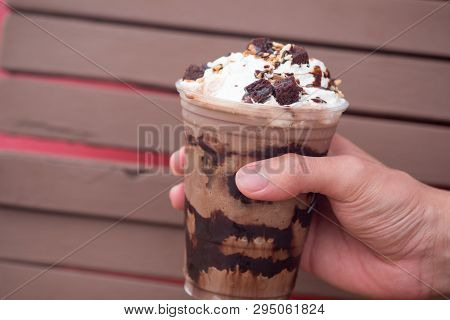 A Delicious Chocolate Frappe In Plastic Cup In Hand