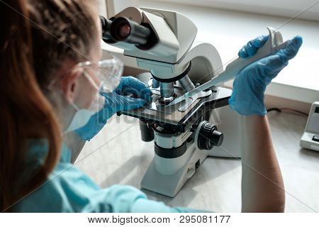 Woman Laborant Working With Microscope Holding Automatic Pipette