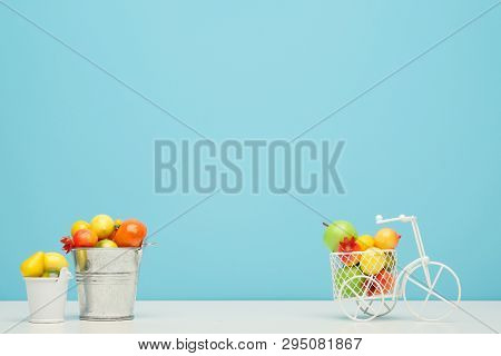 White Wire Bicycle With A Basket Filled With Mini Fruit. Near The Bucket With Vegetables And Fruits.