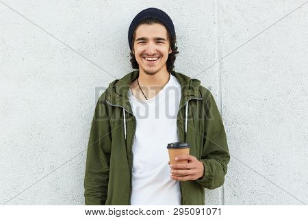 Waist Up Shot Of Laughing Hipster Guy With Curly Black Hair, Wears Green Jacket, White T Shirt, Blac
